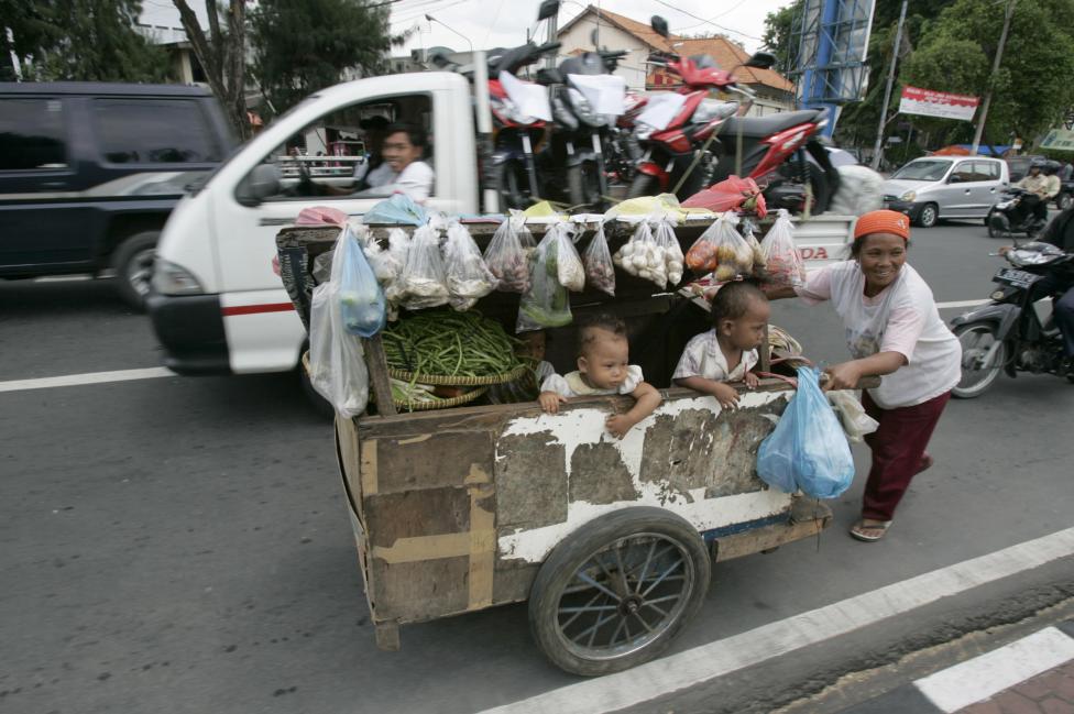 A food seller pushes her cart at a street in Surabaya, Indonesia